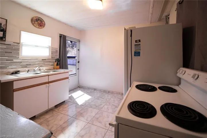 Kitchen featuring white appliances, a sink, light countertops, marble finish floor, and tasteful backsplash