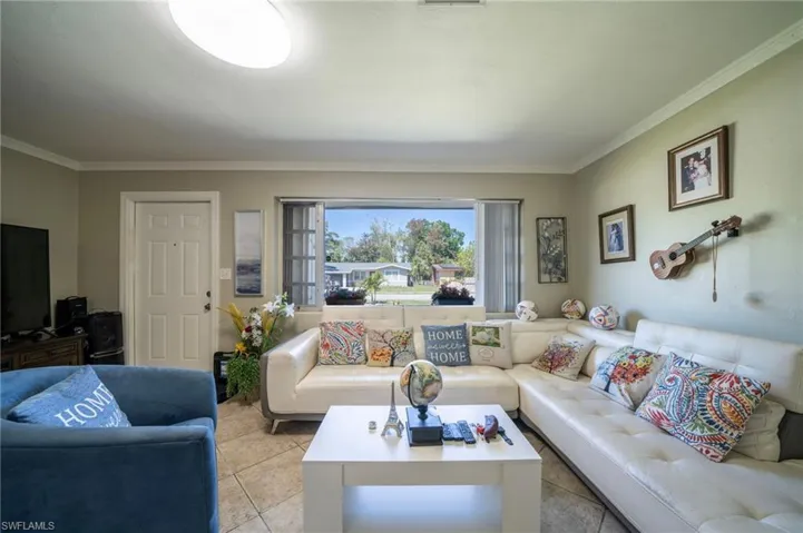 Living room with light tile patterned floors and crown molding