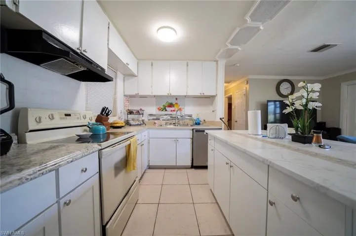 Kitchen featuring white range with electric stovetop, visible vents, white cabinetry, and a sink