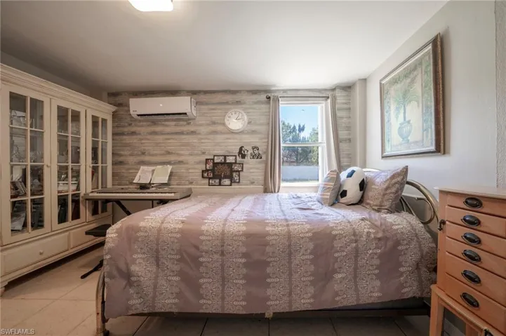 Bedroom featuring an AC wall unit, light tile patterned floors, and wood walls
