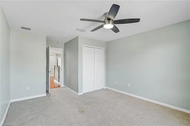 Unfurnished bedroom with light colored carpet, ceiling fan, and a closet