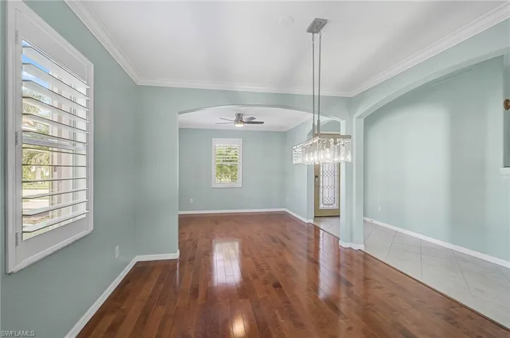 Unfurnished room featuring ceiling fan with notable chandelier, crown molding, and hardwood / wood-style floors