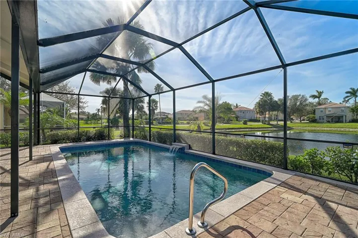 View of pool with a patio, pool water feature, a lanai, and a water view