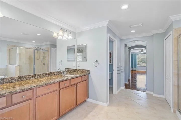 Bathroom with toilet, vanity, a shower with shower door, and ornamental molding