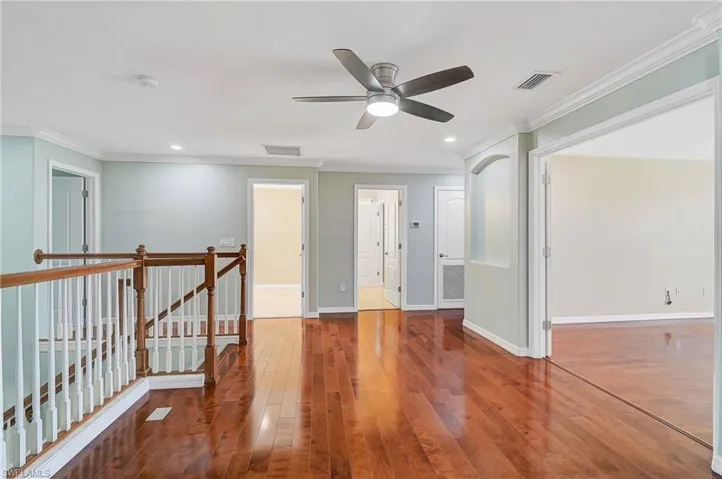 Empty room featuring hardwood / wood-style floors, ceiling fan, and crown molding