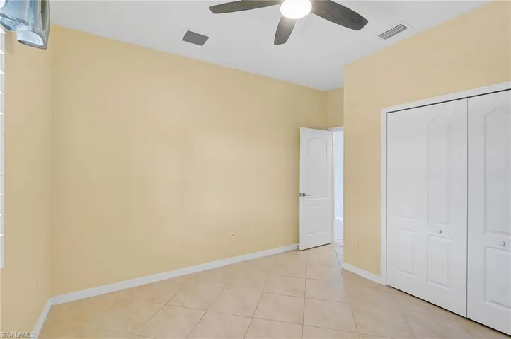 Unfurnished bedroom with ceiling fan, a closet, and light tile patterned floors