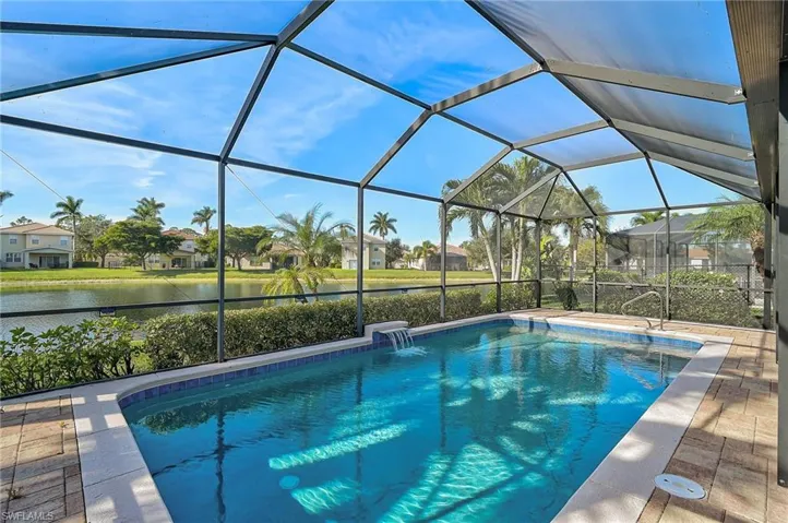 View of swimming pool with a lanai, a patio, pool water feature, and a water view