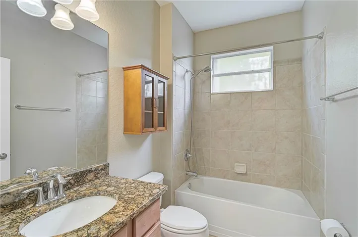Full bathroom featuring tiled shower / bath, vanity, and toilet