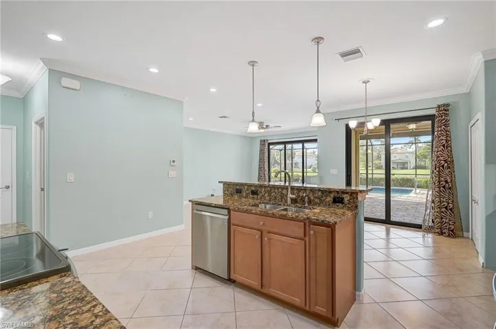 Kitchen with dishwasher, hanging light fixtures, ceiling fan with notable chandelier, dark stone counters, and sink