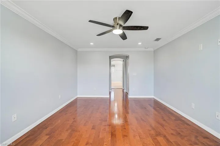Empty room with wood-type flooring, ceiling fan, and ornamental molding