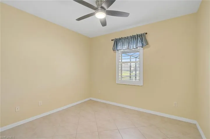 Empty room featuring light tile patterned flooring and ceiling fan