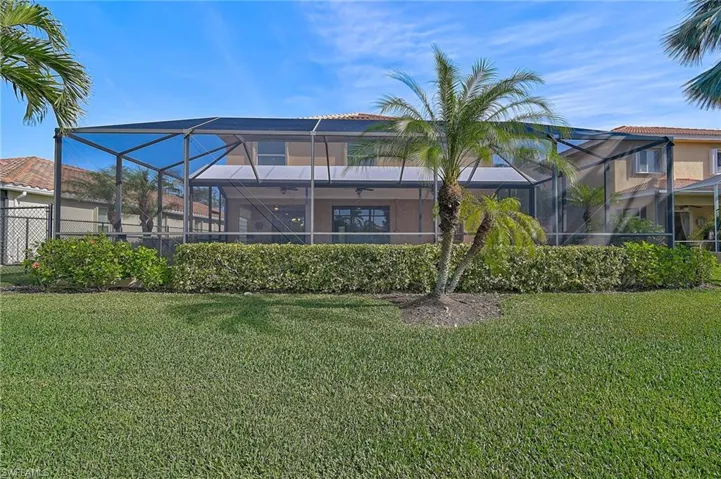 Back of house with glass enclosure and a yard