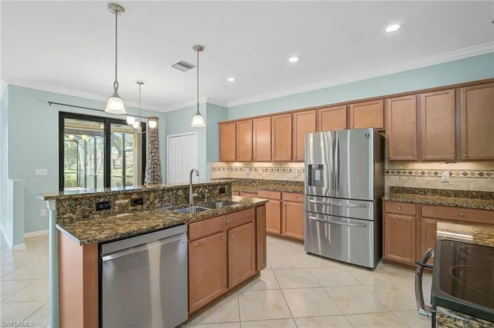 Kitchen featuring pendant lighting, backsplash, appliances with stainless steel finishes, ornamental molding, and sink