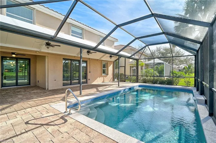 View of swimming pool featuring ceiling fan, a patio, and glass enclosure