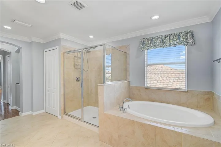 Bathroom with ornamental molding, tile patterned floors, and independent shower and bath