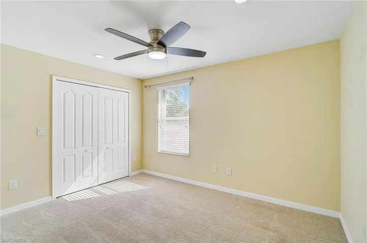 Unfurnished bedroom featuring light colored carpet, ceiling fan, and a closet