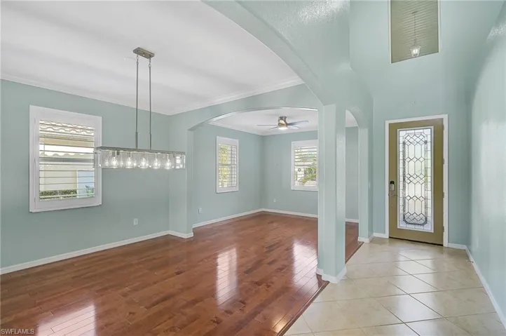 Entrance foyer with ceiling fan with notable chandelier, light wood-type flooring, and ornamental molding