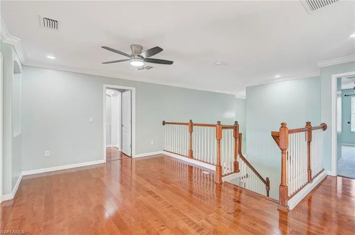 Empty room featuring wood-type flooring, ceiling fan, and crown molding