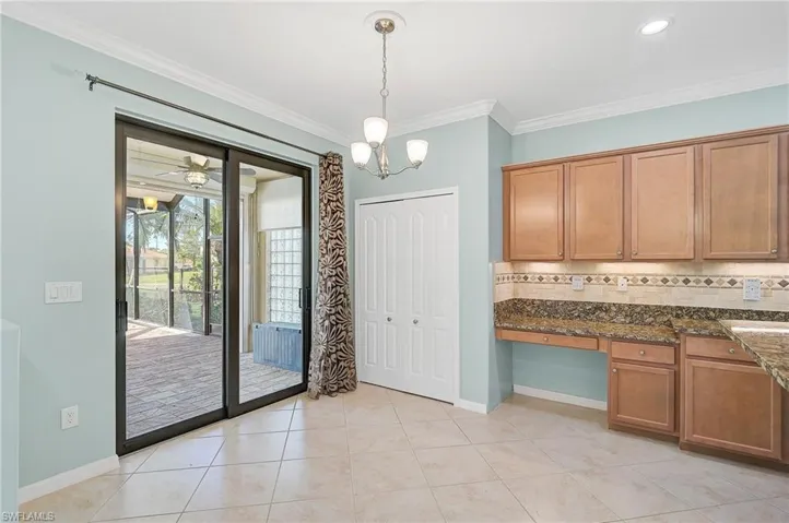 Kitchen with decorative light fixtures, tasteful backsplash, ceiling fan with notable chandelier, ornamental molding, and dark stone countertops