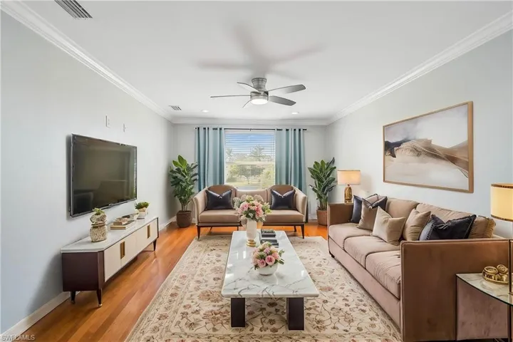 Living room with ornamental molding, ceiling fan, and light wood-type flooring