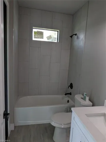 Full bathroom with hardwood / wood-style flooring, vanity, toilet, and tiled shower / bath