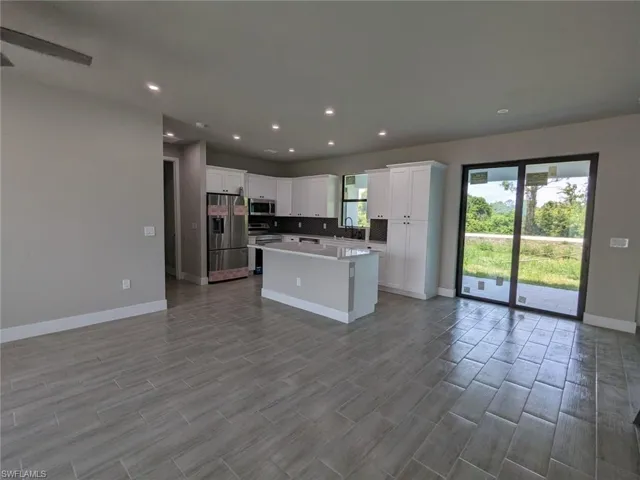Kitchen with a kitchen island, appliances with stainless steel finishes, sink, white cabinets, and decorative backsplash