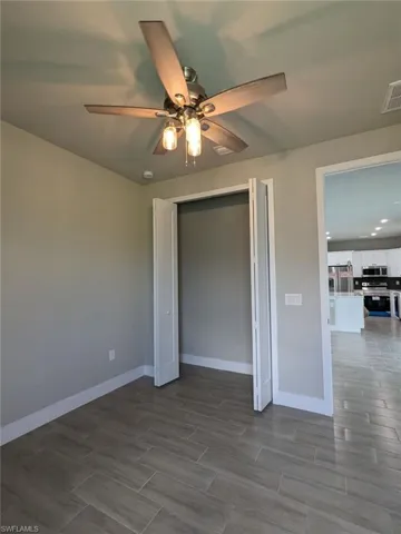 Unfurnished bedroom featuring a closet, ceiling fan, and stainless steel fridge with ice dispenser