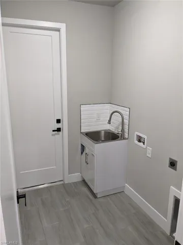 Laundry room with sink, cabinets, hookup for a washing machine, hookup for an electric dryer, and light wood-type flooring