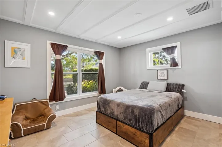 Bedroom with multiple windows, light tile patterned flooring, and beam ceiling