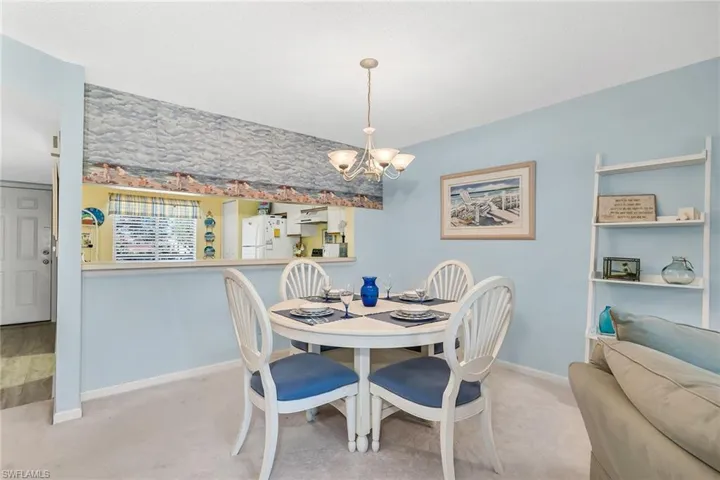 Carpeted dining room with a chandelier and baseboards