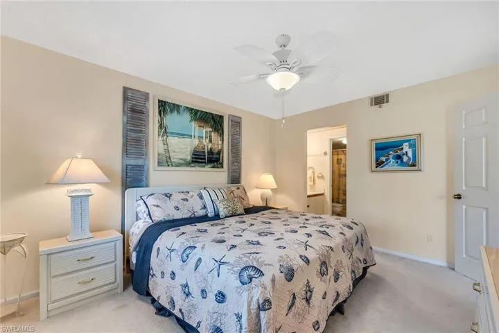Bedroom with light colored carpet, a ceiling fan, and connected bathroom