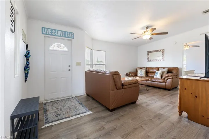 Living area featuring wood finished floors, a ceiling fan, and crown molding