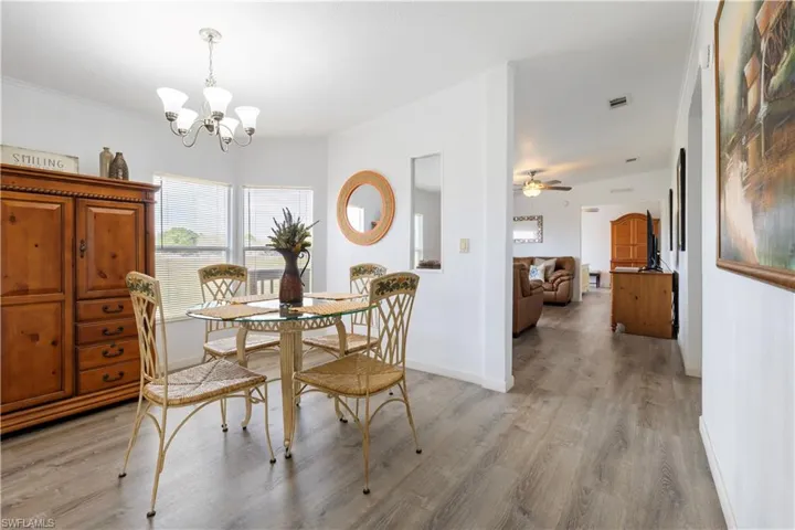 Dining space with light wood-style flooring, crown molding, a chandelier, and a ceiling fan