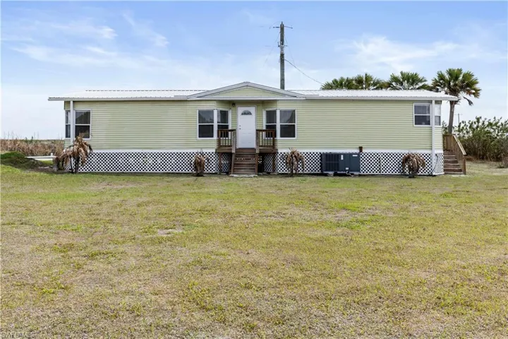 View of front of property featuring a deck, a metal roof, a front yard, and entry steps
