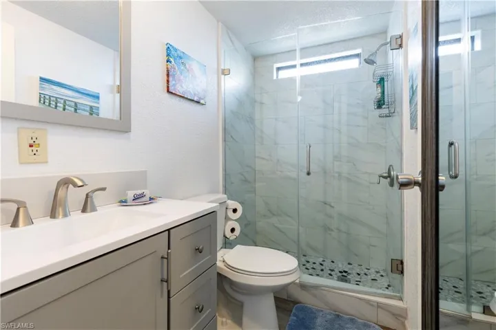 Full bathroom featuring vanity, a marble finish shower, a textured ceiling, and a textured wall