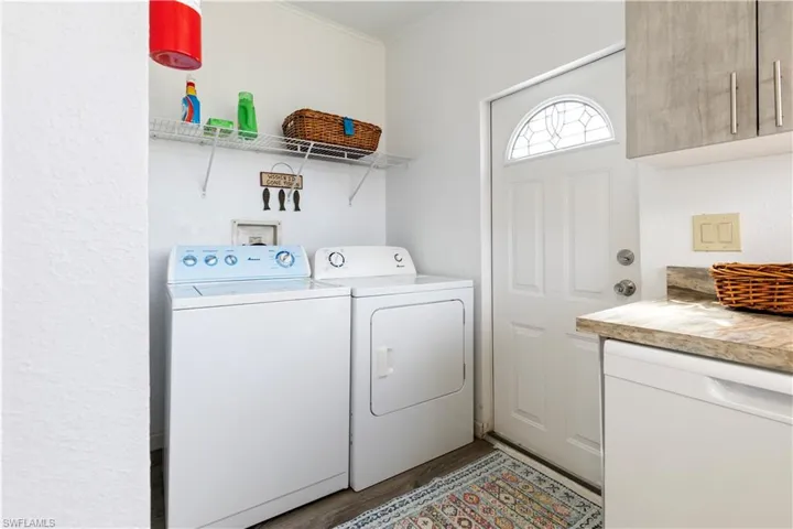 Laundry room with cabinet space, light wood-type flooring, washing machine and clothes dryer, and ornamental molding