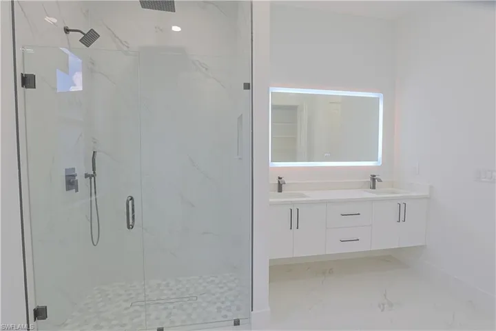 Bathroom featuring a marble finish shower, double vanity, and marble finish floors