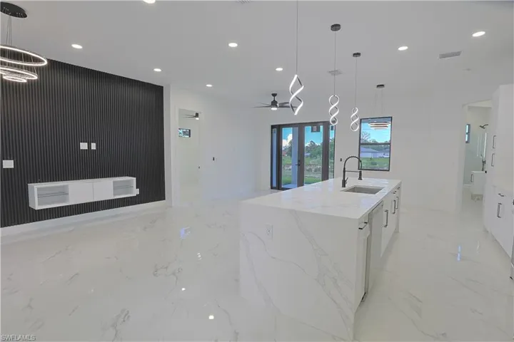 Kitchen with recessed lighting, white cabinetry, open floor plan, light marble finish floors, and ceiling fan