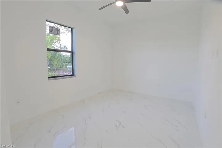 Unfurnished room featuring marble look tiles and a ceiling fan