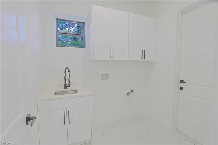 Washroom featuring cabinet space, hookup for an electric dryer, marble finish floors, and washer hookup