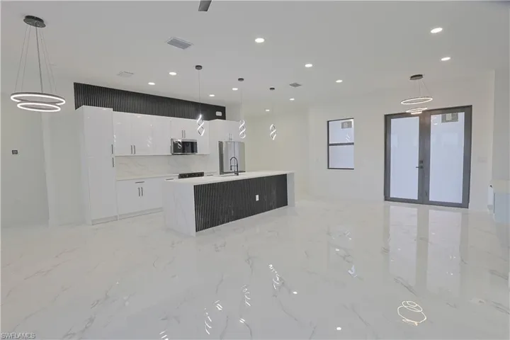 Kitchen with stainless steel appliances, modern cabinets, white cabinetry, a center island with sink, and recessed lighting