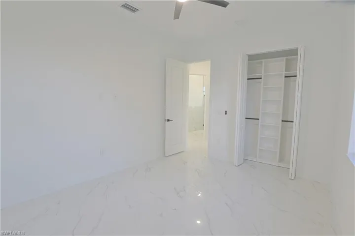 Unfurnished bedroom featuring marble finish flooring, a closet, and a ceiling fan