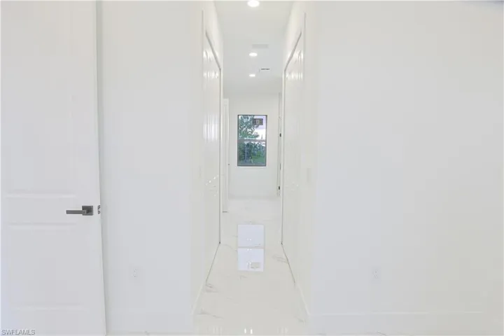 Corridor featuring light marble finish floors and recessed lighting