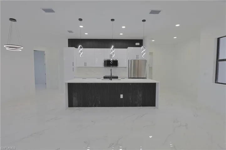 Kitchen featuring stainless steel appliances, white cabinets, modern cabinets, a kitchen island with sink, and light marble finish floors