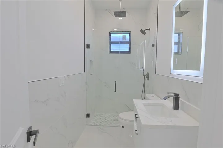 Bathroom with marble finish floors, a marble finish shower, and vanity