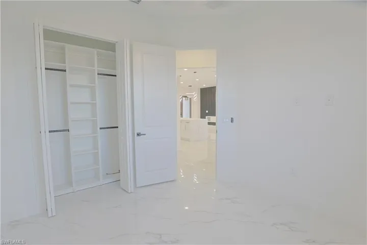 Unfurnished bedroom with light marble finish flooring and a closet