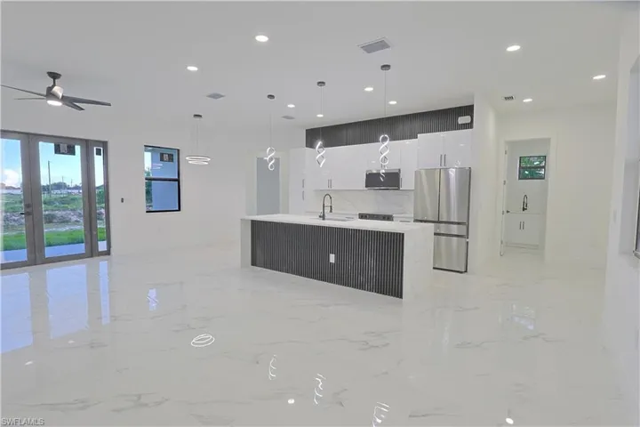 Kitchen featuring appliances with stainless steel finishes, modern cabinets, light marble finish floors, white cabinetry, and ceiling fan