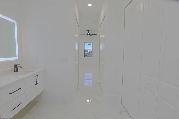 Bathroom with marble look tile flooring, vanity, ceiling fan, and recessed lighting