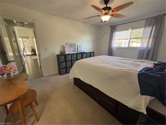 Bedroom featuring carpet, a textured ceiling, and a ceiling fan