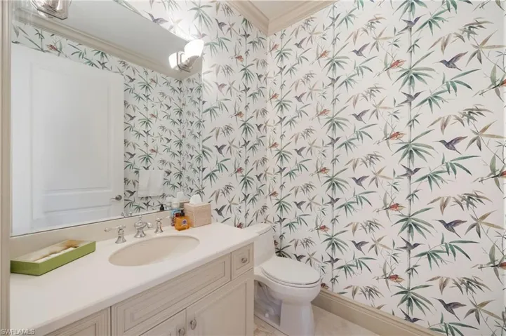Half bath featuring wallpapered walls, vanity, and crown molding